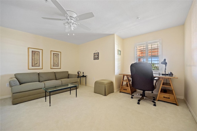 carpeted office space featuring baseboards and ceiling fan