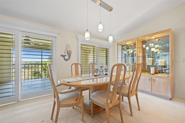 dining area with baseboards, light colored carpet, and lofted ceiling