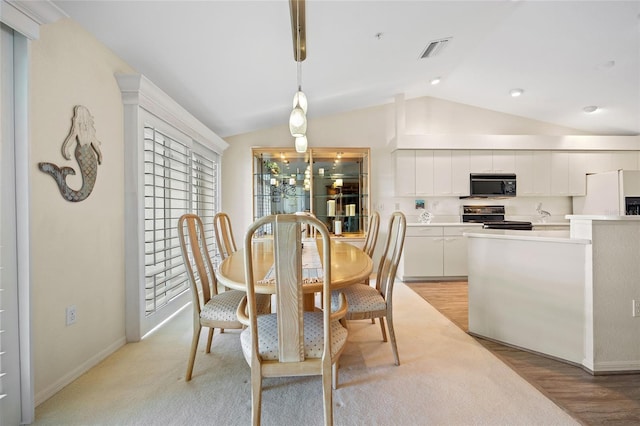 dining space with visible vents, baseboards, lofted ceiling, and light wood-type flooring
