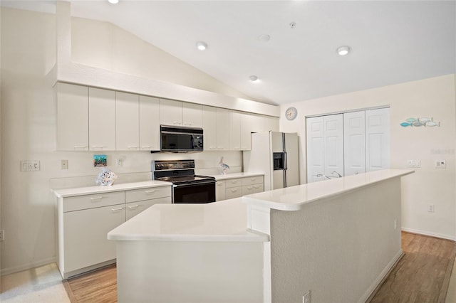 kitchen with lofted ceiling, light wood-style floors, baseboards, light countertops, and black appliances
