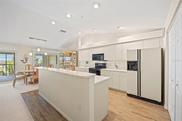 kitchen featuring black microwave, white fridge with ice dispenser, a center island, electric stove, and lofted ceiling