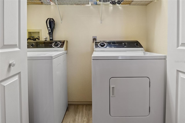 clothes washing area featuring independent washer and dryer, laundry area, baseboards, and wood finished floors