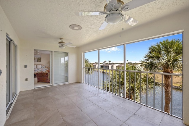 unfurnished sunroom with a water view, tile patterned floors, and a textured ceiling
