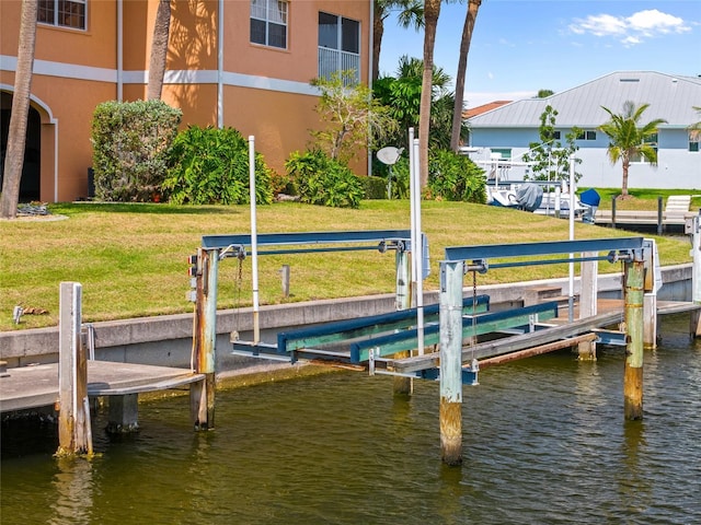 view of dock featuring a lawn, boat lift, and a water view