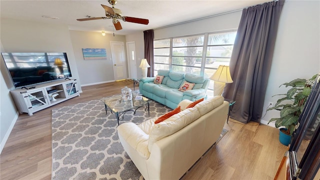 living room with light wood-style flooring, a ceiling fan, and baseboards