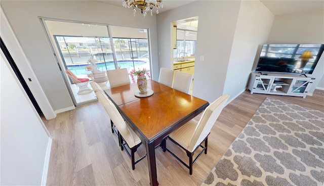 dining area featuring a chandelier, light wood-type flooring, and baseboards