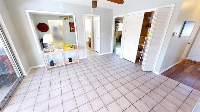 interior space featuring baseboards, ceiling fan, and light tile patterned floors