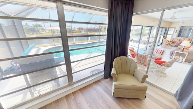 living area featuring a ceiling fan, a sunroom, wood finished floors, and a water view
