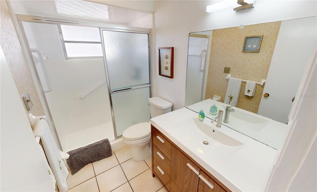 bathroom featuring a shower stall, toilet, vanity, and tile patterned floors