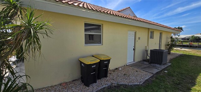 view of property exterior with a tiled roof, central AC, and stucco siding