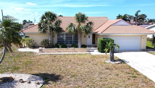 view of front of house with an attached garage, a tile roof, a front lawn, and driveway