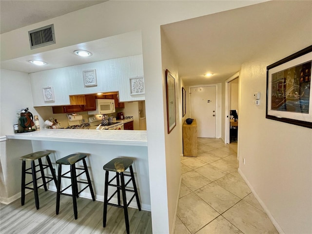 25188 Marion Ave Unit F304, Punta Gorda, FL 33950 - kitchen featuring light tile patterned floors, a breakfast bar area, visible vents, and white appliances
