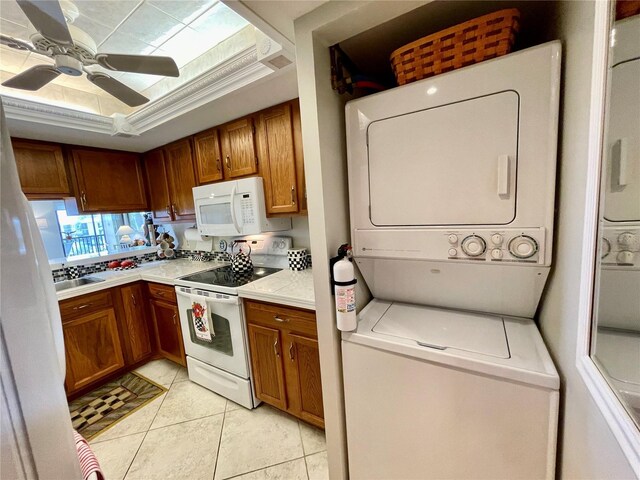 25188 Marion Ave Unit F304, Punta Gorda, FL 33950 - kitchen with light countertops, stacked washing maching and dryer, light tile patterned flooring, white appliances, and brown cabinetry