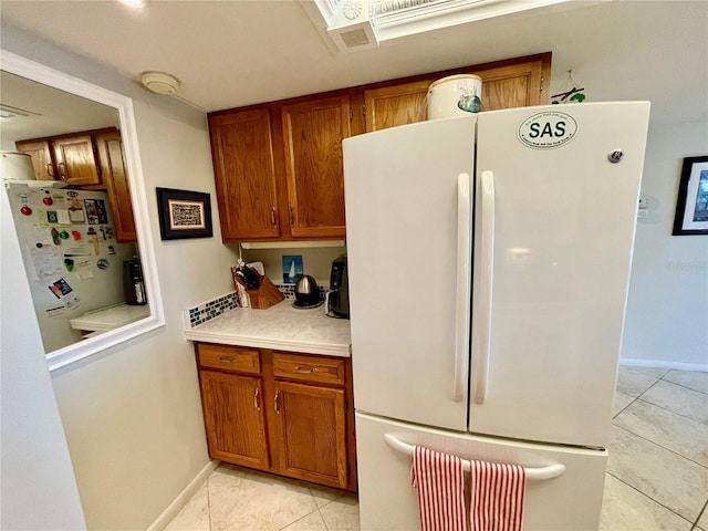 25188 Marion Ave Unit F304, Punta Gorda, FL 33950 - kitchen with light tile patterned floors, brown cabinets, freestanding refrigerator, and light countertops