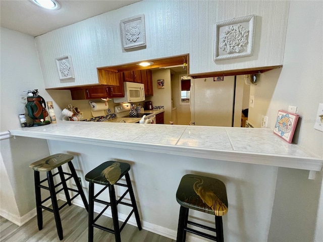 25188 Marion Ave Unit F304, Punta Gorda, FL 33950 - kitchen with a kitchen breakfast bar, light wood-style floors, white appliances, and baseboards