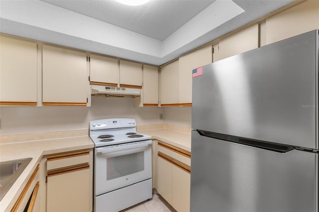 19505 Quesada Ave Unit A204, Port Charlotte, FL 33948 - kitchen featuring under cabinet range hood, white electric range oven, cream cabinetry, light countertops, and freestanding refrigerator