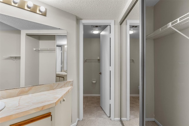 19505 Quesada Ave Unit A204, Port Charlotte, FL 33948 - bathroom with visible vents, vanity, a walk in closet, and baseboards
