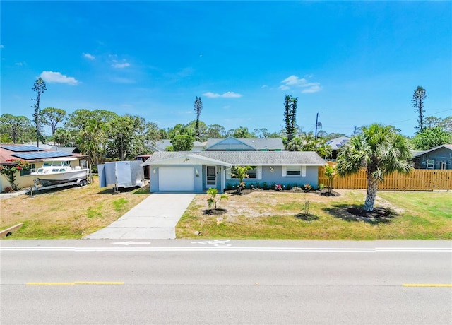 single story home featuring concrete driveway, an attached garage, fence, and a front lawn