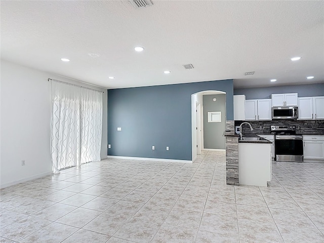 3514 Yacht Club Ct, Kissimmee, FL 34746 - kitchen featuring backsplash, dark countertops, arched walkways, appliances with stainless steel finishes, and open floor plan