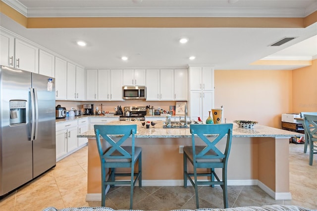 kitchen featuring an island with sink, appliances with stainless steel finishes, white cabinets, a sink, and visible vents