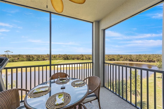 sunroom with golf course view and a water view