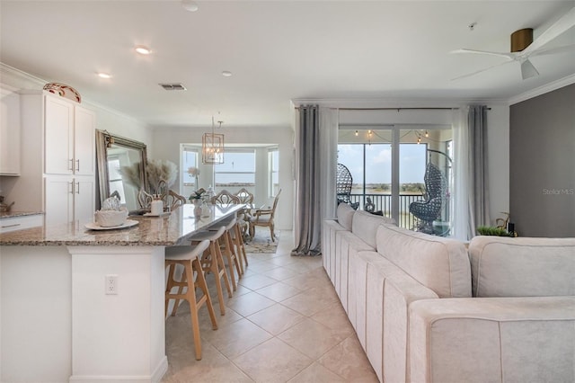 living area featuring visible vents, ornamental molding, plenty of natural light, and ceiling fan