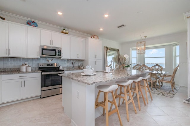 kitchen with tasteful backsplash, stainless steel appliances, white cabinetry, and visible vents