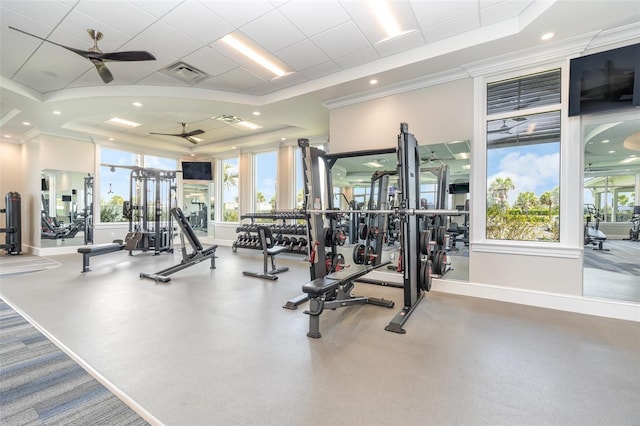 exercise room featuring baseboards, a raised ceiling, ceiling fan, and a healthy amount of sunlight