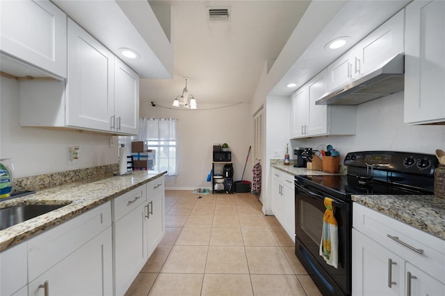 2751 S Cranberry Blvd, North Port, FL 34286 - kitchen with black range with electric cooktop, under cabinet range hood, light tile patterned floors, white cabinets, and recessed lighting