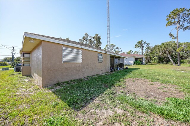2751 S Cranberry Blvd, North Port, FL 34286 - view of side of property with stucco siding, a lawn, and central AC unit