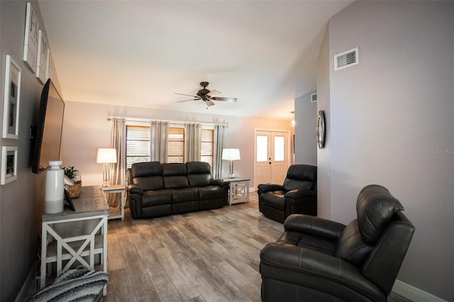 living room featuring baseboards, visible vents, wood finished floors, and a ceiling fan