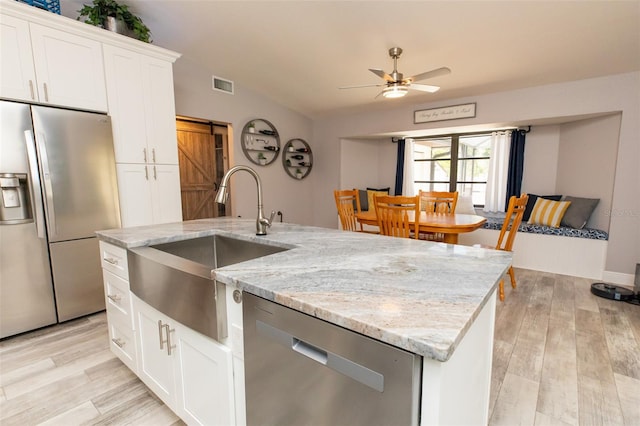 kitchen with an island with sink, stainless steel appliances, a sink, visible vents, and a ceiling fan