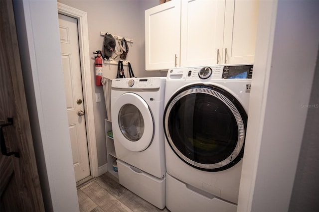washroom featuring light wood-style floors, cabinet space, and independent washer and dryer