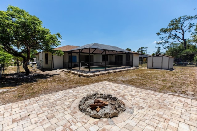 rear view of property with an outdoor fire pit, a fenced backyard, a storage unit, an outbuilding, and a patio