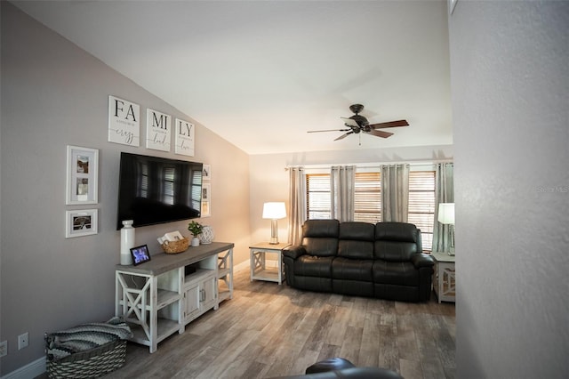 living room with ceiling fan, vaulted ceiling, wood finished floors, and baseboards