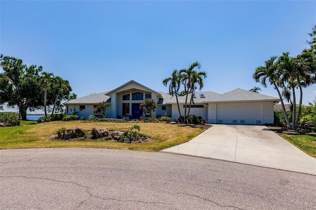 single story home with a front yard, concrete driveway, and a garage