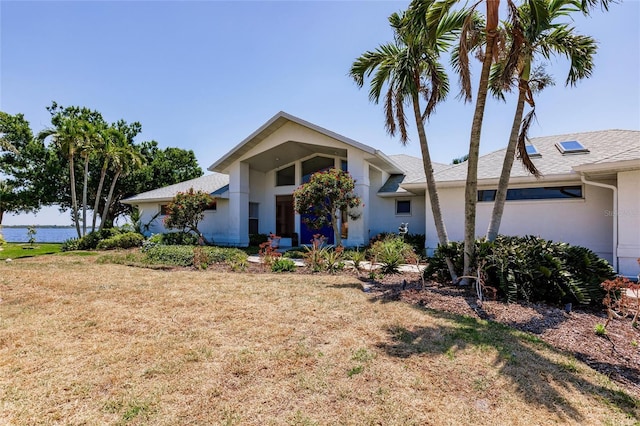 view of front of property featuring a front lawn, stucco siding, and a water view