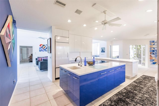 kitchen with paneled refrigerator, modern cabinets, ceiling fan, visible vents, and a kitchen island with sink