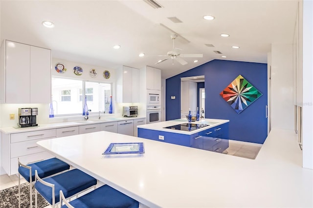 kitchen with vaulted ceiling, modern cabinets, a kitchen island, and white appliances