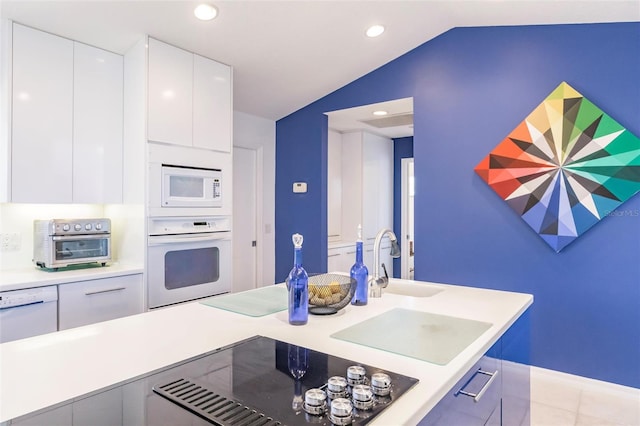 kitchen featuring modern cabinets, white appliances, a toaster, white cabinets, and lofted ceiling
