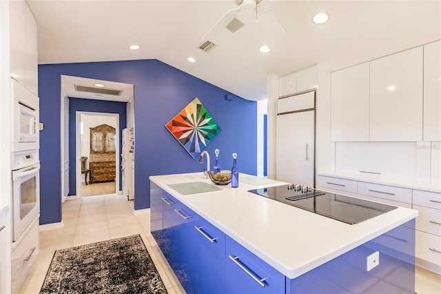 kitchen with a sink, modern cabinets, white appliances, blue cabinets, and an island with sink