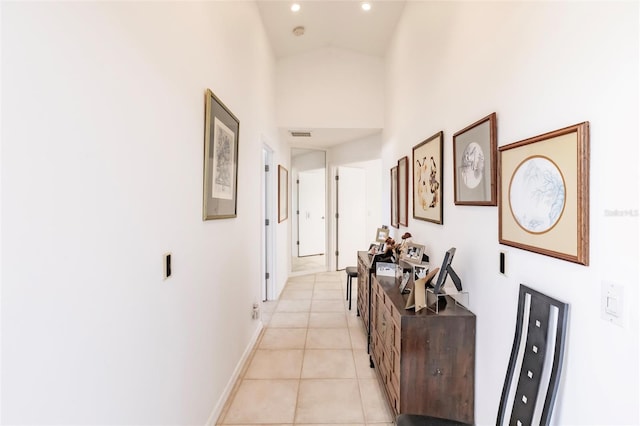 hallway with light tile patterned floors, visible vents, baseboards, recessed lighting, and a high ceiling