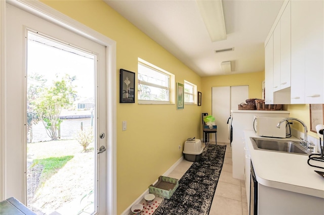 kitchen featuring a sink, light tile patterned flooring, visible vents, light countertops, and white cabinets