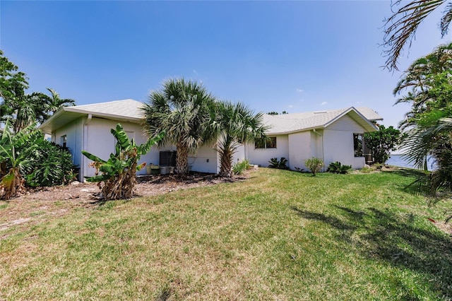rear view of property with stucco siding and a yard