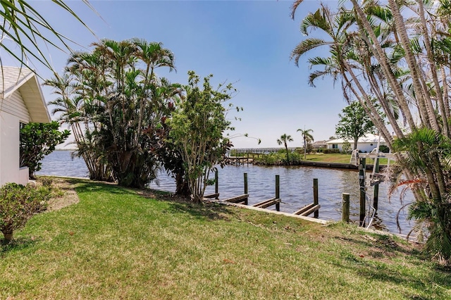 view of dock with a yard and a water view