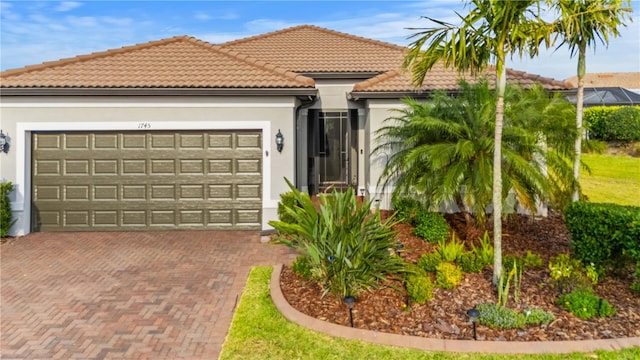 1745 Hyssop Loop, North Port, FL 34289 - mediterranean / spanish-style house featuring a garage, decorative driveway, stucco siding, and a tiled roof