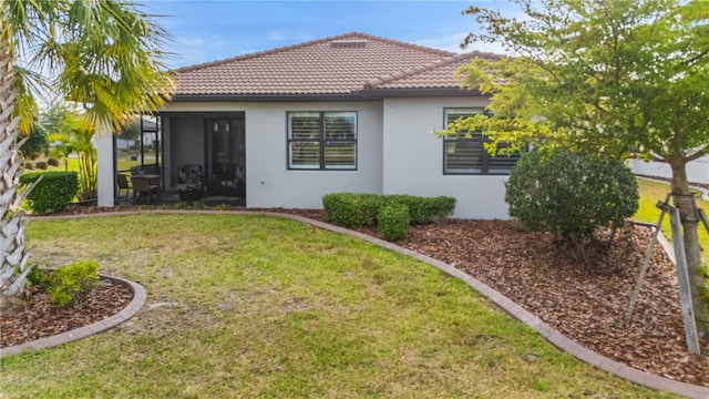 1745 Hyssop Loop, North Port, FL 34289 - back of property featuring stucco siding, a sunroom, a lawn, and a tile roof