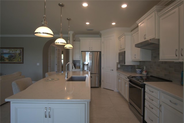 1745 Hyssop Loop, North Port, FL 34289 - kitchen with appliances with stainless steel finishes, under cabinet range hood, arched walkways, tasteful backsplash, and white cabinets