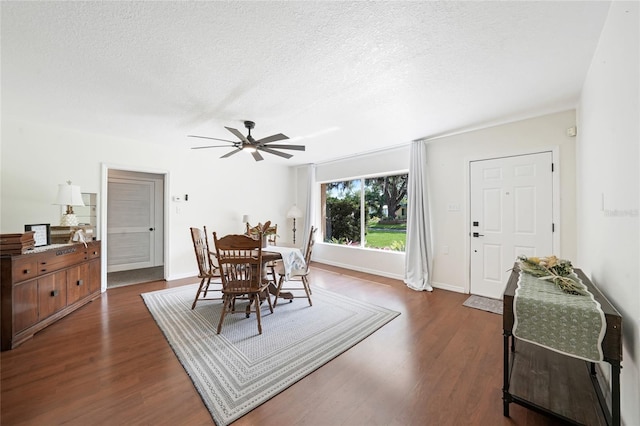 dining room featuring dark wood-style floors, a textured ceiling, ceiling fan, and baseboards