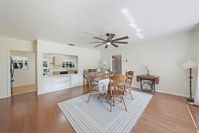 dining space with visible vents, wood finished floors, and a ceiling fan